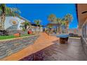Lush backyard area with stone accents, concrete patio, landscaping, outdoor lounge space, and mature trees at 516 Arizona St, Boulder City, NV 89005