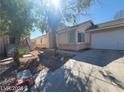 Inviting single-story home with a well-kept lawn, a two-car garage, and mature trees adding to the curb appeal at 5316 Clover Blossom Ct, North Las Vegas, NV 89031