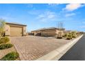 Spacious three-car garage with brick-paved driveway and desert landscaping at 5860 Noah Springs Ct, Las Vegas, NV 89149