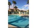 Community pool with clear blue water, palm trees, and a covered seating area at 8410 Eldora Ave # 2067, Las Vegas, NV 89117