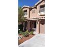 Tan two-story home featuring a two car garage, balcony, desert landscaping and covered front porch entry at 9758 Panther Hollow St, Las Vegas, NV 89141