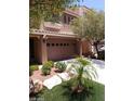 Tan two-story home with a two-car garage, desert landscaping, and a concrete driveway at 9758 Panther Hollow St, Las Vegas, NV 89141
