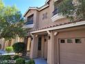 Tan two-story home featuring a two car garage, balcony, desert landscaping and covered front porch entry at 9758 Panther Hollow St, Las Vegas, NV 89141