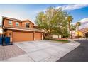 Expansive driveway leading to a three-car garage, complemented by mature trees and desert landscaping at 1017 Fairbury St, Henderson, NV 89052