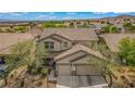 Aerial view of a two-story home featuring a two-car garage with lush landscaping at 10385 Grassyrock Ct, Las Vegas, NV 89129