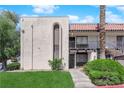 View of the stucco condo with a red tile roof, balcony, arched windows, and verdant landscaping at 1440 Vegas Valley Dr # 1, Las Vegas, NV 89169