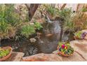 Koi pond with waterfall feature and landscaping with colorful plants in pots at 5050 Secret Rock St, Las Vegas, NV 89122