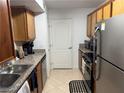Galley kitchen with stainless appliances, wood cabinets, and diagonal tile floors at 5055 W Hacienda Ave # 2175, Las Vegas, NV 89118