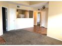 Open-concept living room featuring neutral carpet and wood flooring, leading into the kitchen and other rooms at 6955 Durango Dr # 3092, Las Vegas, NV 89149