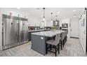 Bright kitchen with stainless steel appliances, an island with marble countertop, and gray cabinets at 6995 Rogers St, Las Vegas, NV 89118