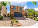 A two-story home features a dark garage door and desert landscaping, with a brick paved driveway at 7322 Dazzle Point St, North Las Vegas, NV 89084