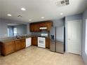 Cozy kitchen featuring stainless steel refrigerator, tile flooring, and light wood cabinets at 8089 Windmill Villa St, Las Vegas, NV 89139