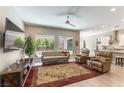 Comfortable living room with a modern ceiling fan, plush seating, and large windows overlooking the backyard at 11161 Black Fire Opal Dr, Las Vegas, NV 89138