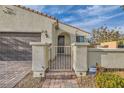 Close-up of the front entrance featuring a decorative gate, brick pathway, and stucco pillars, creating a welcoming facade at 130 Mountain Cedar Ct, North Las Vegas, NV 89031