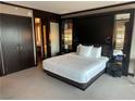 Modern bedroom featuring a king-size bed with white linens and dark wood accents and a glimpse into the bathroom at 2600 W Harmon Ave # 25019, Las Vegas, NV 89158