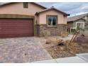 Lovely home featuring a stone facade, a brick driveway, a two-car garage and well-kept landscaping at 2748 Brinkley Manor St, Laughlin, NV 89029