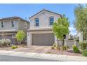 Home featuring a two-car garage, brick driveway, desert landscaping, and stucco exterior at 406 Misterioso St, Henderson, NV 89011