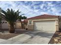 Exterior showcasing a low-maintenance desert landscape, red-tiled roof, and an attached two-car garage at 6119 Magic Mesa St, North Las Vegas, NV 89031