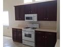 Kitchen featuring modern white appliances, dark wood cabinets, and laminate countertops at 6119 Magic Mesa St, North Las Vegas, NV 89031