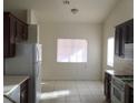 Bright kitchen area featuring tiled floors, dark cabinetry, white appliances, and lots of natural light at 6119 Magic Mesa St, North Las Vegas, NV 89031