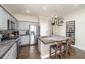 Well-lit kitchen with gray cabinets, tiled backsplash, stainless steel appliances, and island featuring a hanging pot rack at 10633 Tinta Ln, Las Vegas, NV 89144