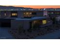 Striking modern home showcasing desert landscaping and illuminated facade, creating a welcoming nighttime ambiance at 21 Rockstream Dr, Henderson, NV 89012