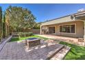 Relaxing backyard featuring a stone fire pit, built-in grill, and artificial turf perfect for low-maintenance enjoyment at 3 Glendora Ct, Henderson, NV 89052