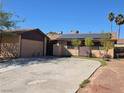 Single-story home with a two car garage, solar panels, and a spacious driveway on a sunny day at 5594 Ricochet Ave, Las Vegas, NV 89110