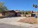 Single-story home with a two car garage, solar panels, and a spacious driveway on a sunny day at 5594 Ricochet Ave, Las Vegas, NV 89110