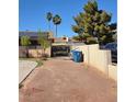 A view of the side yard with a stucco wall with a gate, desert landscaping, and solar panels on the roof at 5594 Ricochet Ave, Las Vegas, NV 89110