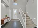A bright and airy entryway with a staircase, gray tile floors, and neutral paint provides a calming welcome at 9221 Steeltree St, Las Vegas, NV 89143