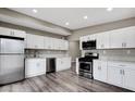 Modern kitchen with stainless steel appliances, white cabinets, and stylish gray wood-look flooring at 2990 La Canada St, Las Vegas, NV 89169