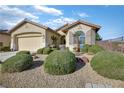 Single-story home features a well-kept yard with mature shrubbery and desert landscaping at 3841 Budenny Dr, Las Vegas, NV 89122