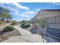 Landscaped walkway to houses with desert landscaping; bench for neighborhood view at 3841 Budenny Dr, Las Vegas, NV 89122