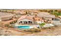 Aerial view of the home showcasing the backyard pool, covered patio, desert landscaping, and neighborhood at 5755 E La Campana Dr, Pahrump, NV 89061