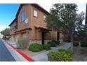 Two-story condo featuring a three-car garage and desert landscaping at 7322 Fools Gold St # 102, Las Vegas, NV 89149