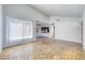 Spacious living room with brick floors leading to kitchen and dining area, illuminated by natural light at 1501 Living Desert Dr # A, Las Vegas, NV 89119