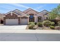 Charming home showcasing a stone facade, well-manicured landscaping, and a spacious three-car garage at 2197 Big Bar Dr, Henderson, NV 89052