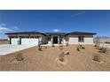 Charming single-story home featuring a three car garage, desert landscaping, and a modern front door at 2900 W Jaybird St, Pahrump, NV 89048