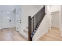Bright entryway showcasing light wood floors, white walls, a modern front door, and a carpeted staircase at 3359 Via Tizzoni St, Henderson, NV 89044