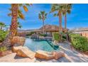 Resort-style backyard pool and spa area surrounded by lush landscaping and palm trees on a sunny day at 8348 Mountain Destiny Ave, Las Vegas, NV 89131
