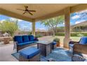 Comfortable covered patio area with plush blue seating, a ceiling fan, and views of the serene backyard at 10201 Los Padres Pl, Las Vegas, NV 89134