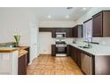 Well-lit kitchen with stainless steel appliances, dark wood cabinetry, and tile floors at 10719 Tottenham Ave, Las Vegas, NV 89135