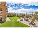 Backyard with a cozy fire pit, comfortable seating, artificial turf, and privacy fencing at 12401 Ferry Glide Ave, Las Vegas, NV 89138