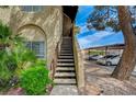 Exterior view of condo with stairs, covered parking, desert landscaping, and mature trees at 5071 Pioneer Ave # 203, Las Vegas, NV 89146