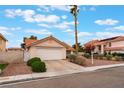 A single-story home featuring a two-car garage, desert landscaping, well-manicured greenery and red clay tile roofing at 1335 Heather Oaks Way, North Las Vegas, NV 89031