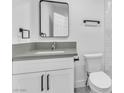 Bathroom features a new white vanity with gray countertop, square mirror, modern fixtures, and white toilet with textured wall panel at 244 N 19Th St, Las Vegas, NV 89101