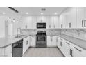 Modern kitchen features white cabinetry, stainless steel appliances, gray quartz countertops and marble backsplash at 244 N 19Th St, Las Vegas, NV 89101