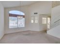 Spacious living room featuring large windows, a chandelier, and access to a staircase at 8012 Pottery Creek Dr, Las Vegas, NV 89128
