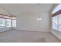 Bright living room with a vaulted ceiling, large windows, and a decorative chandelier at 8012 Pottery Creek Dr, Las Vegas, NV 89128